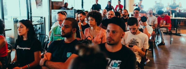 A diverse group of adults attentively participating in an indoor seminar or conference.