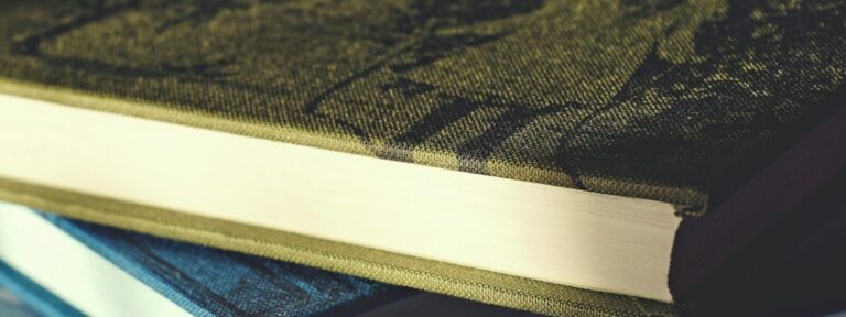 Close-up view of two hardcover books stacked on a patterned surface.